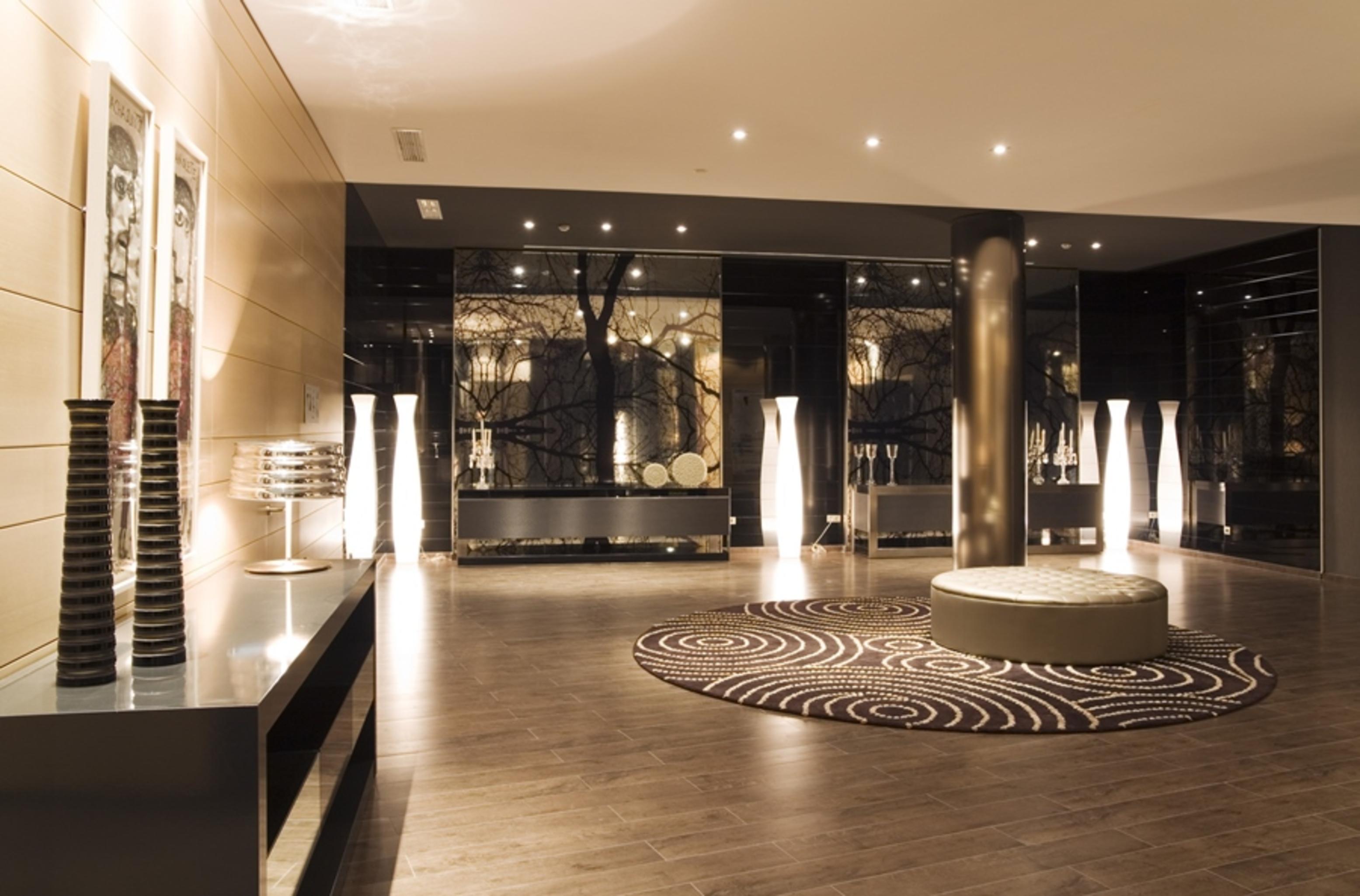 Eurostars Palace Cordoba Luaran gambar The photo shows a modern interior space, likely a lobby or waiting area. The design features polished wooden flooring and sleek surfaces. There are tall, artistic light fixtures scattered throughout, contributing to a sophisticated ambiance. A round 